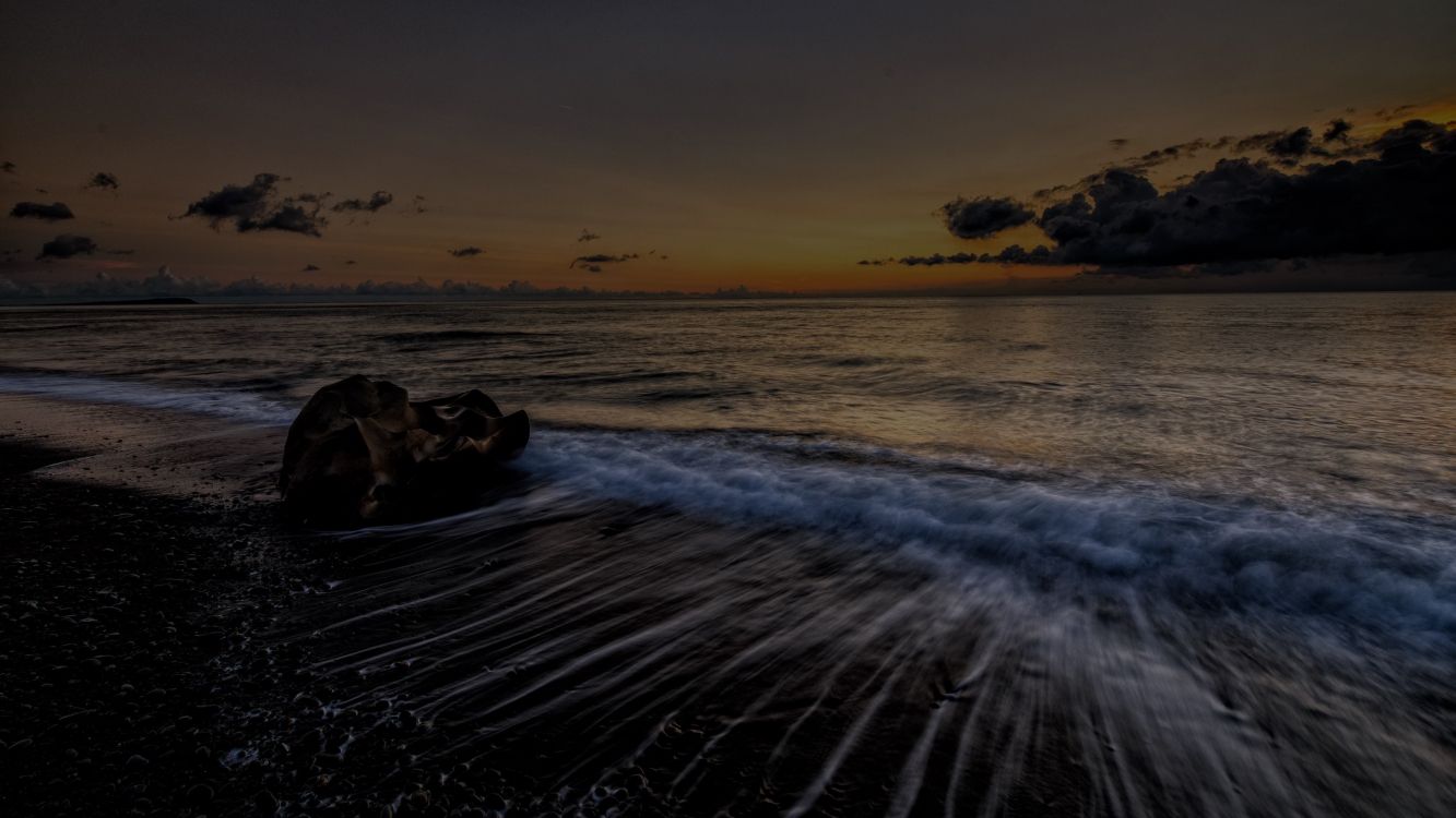 ocean waves crashing on shore during sunset