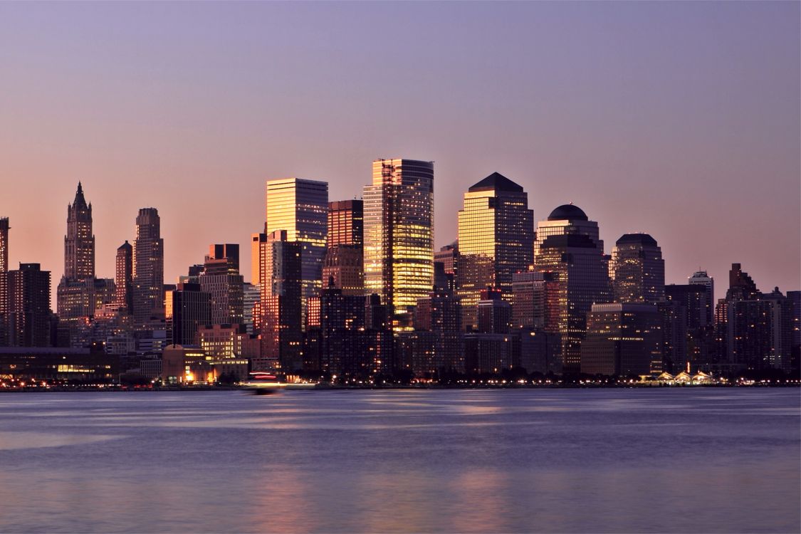 city skyline across body of water during night time