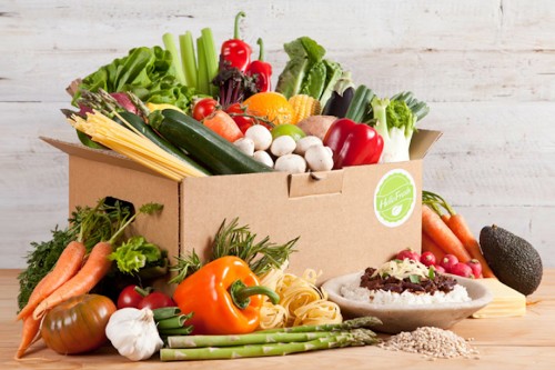 Image red tomato beside green chili and red pepper on brown cardboard box