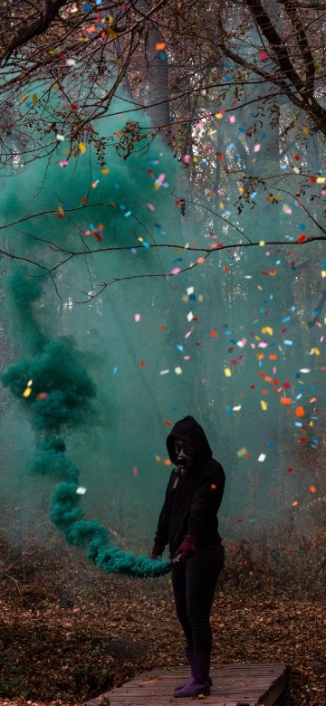 Image woman in black jacket standing under green and pink string lights