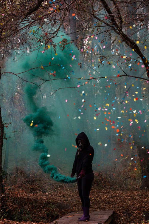 Image woman in black jacket standing under green and pink string lights