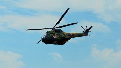 Image green and black camouflage military helicopter flying in the sky