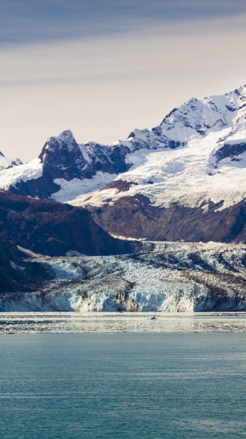 Image snow covered mountain near body of water during daytime