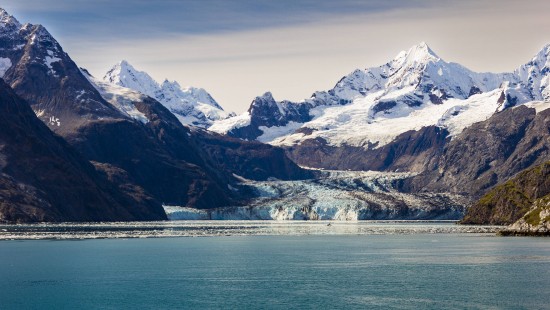 Image snow covered mountain near body of water during daytime