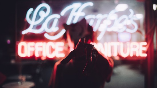 Image person in red jacket standing in front of red and white neon light signage