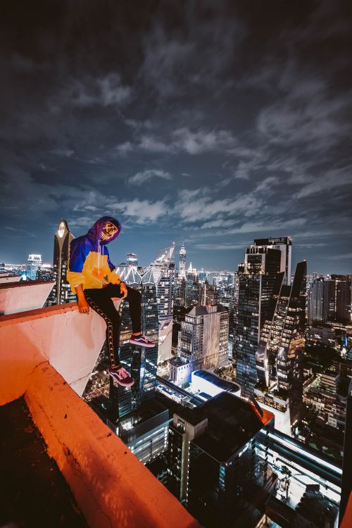Man in Blue Long Sleeve Shirt and Black Pants Standing on Top of Building During Night. Wallpaper in 4000x6000 Resolution