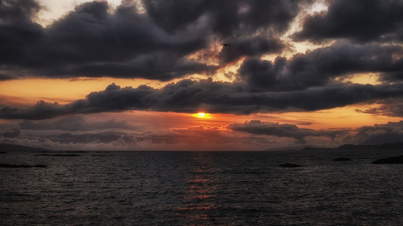 body of water under cloudy sky during sunset