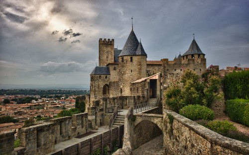 Image gray concrete castle near green trees under cloudy sky during daytime