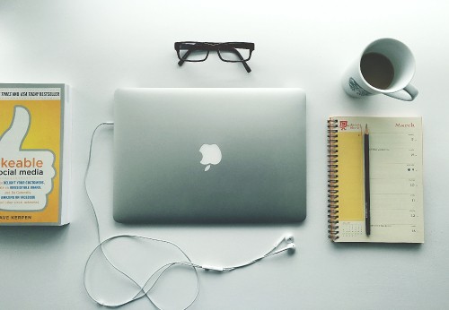 Image silver macbook beside black framed eyeglasses