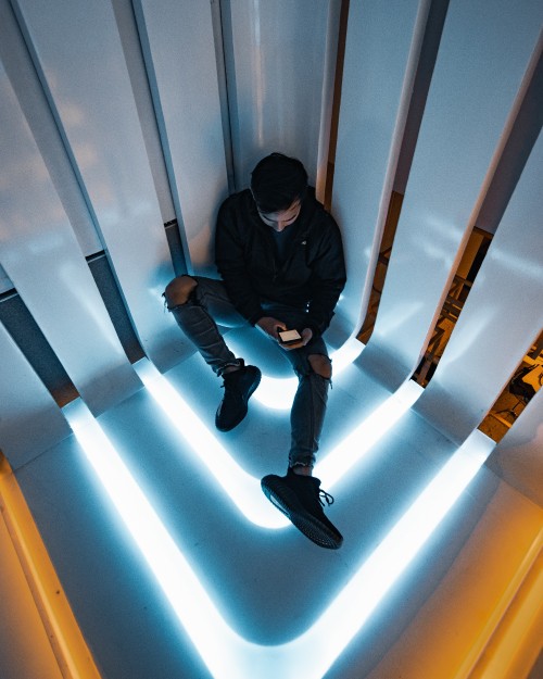 Image man in black jacket and black pants sitting on white wall