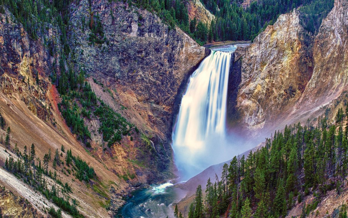 waterfalls between green and brown mountains during daytime