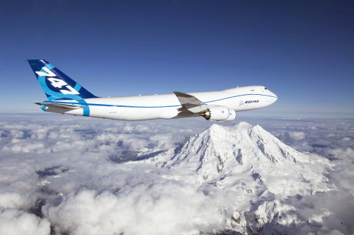 Image white and blue airplane flying over snow covered mountain during daytime