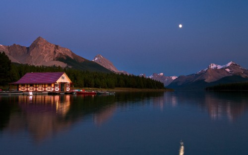 Image red and brown house near lake and green mountains during daytime