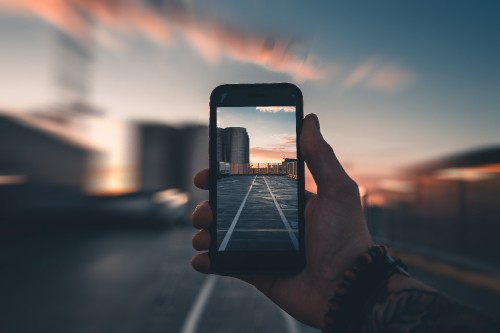 Image person holding iphone taking photo of sunset