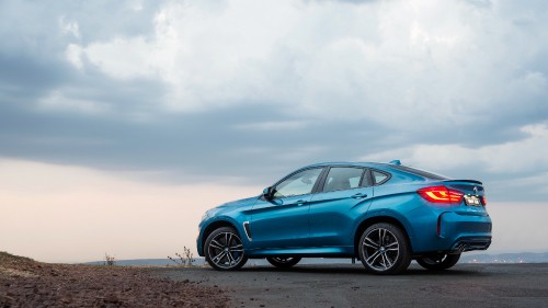 Image blue sedan on brown field under white clouds during daytime