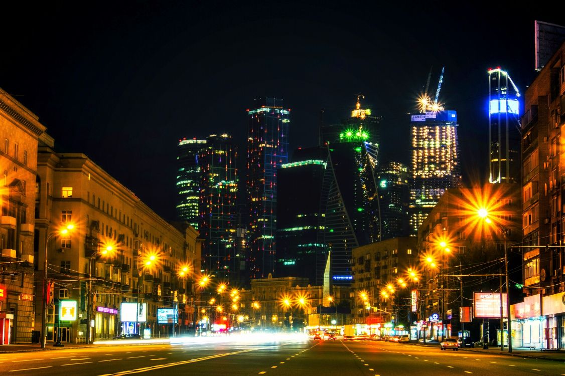 cars on road near high rise buildings during night time