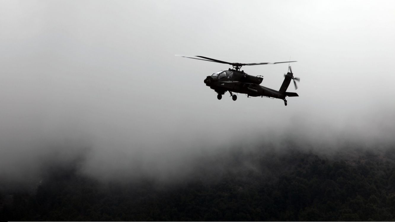 black helicopter flying over the clouds