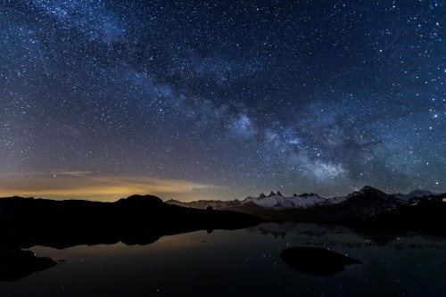 Image silhouette of mountain near body of water under starry night