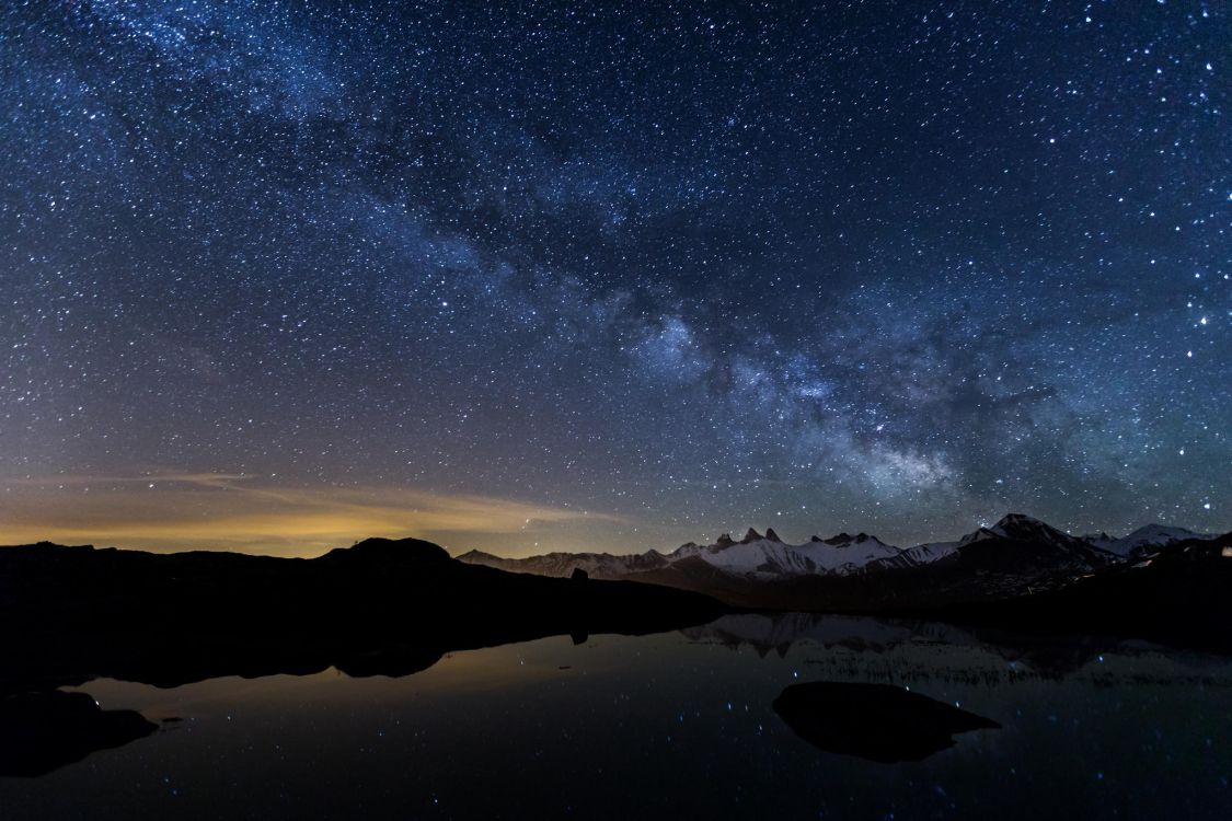 silhouette of mountain near body of water under starry night