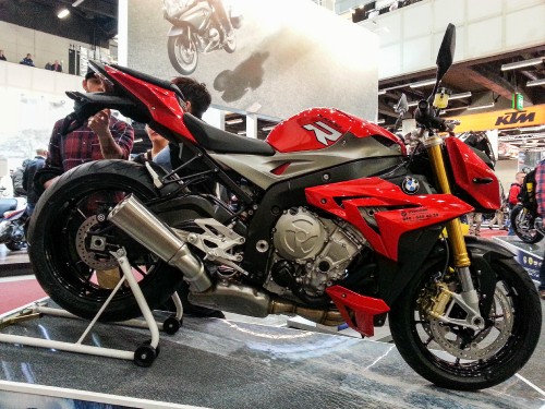 Image red and black sports bike parked beside white wall