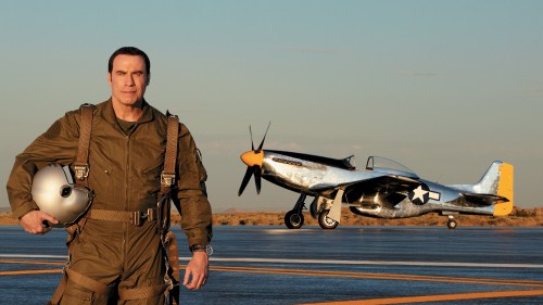 Image man in brown jacket standing beside gray and orange plane