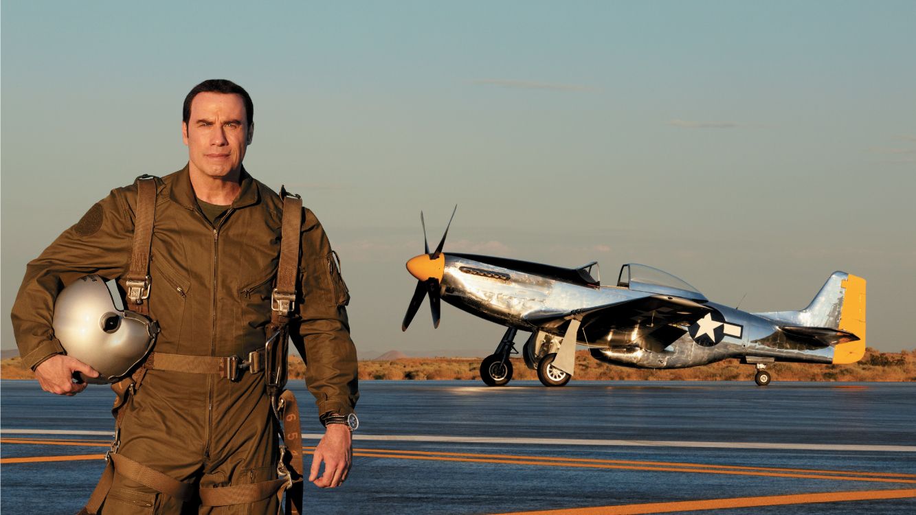 man in brown jacket standing beside gray and orange plane