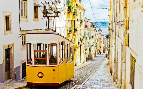 Image yellow and white tram on road during daytime