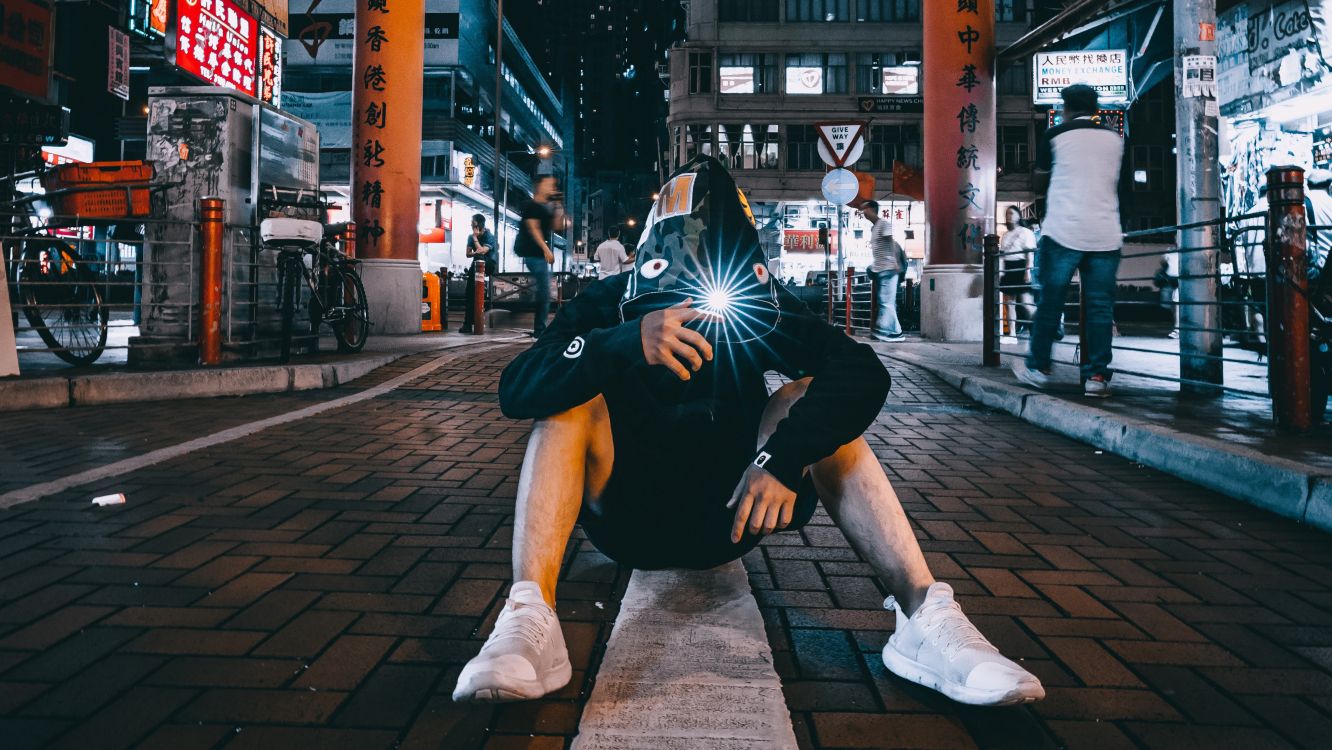 man in black and white nike backpack sitting on sidewalk during daytime