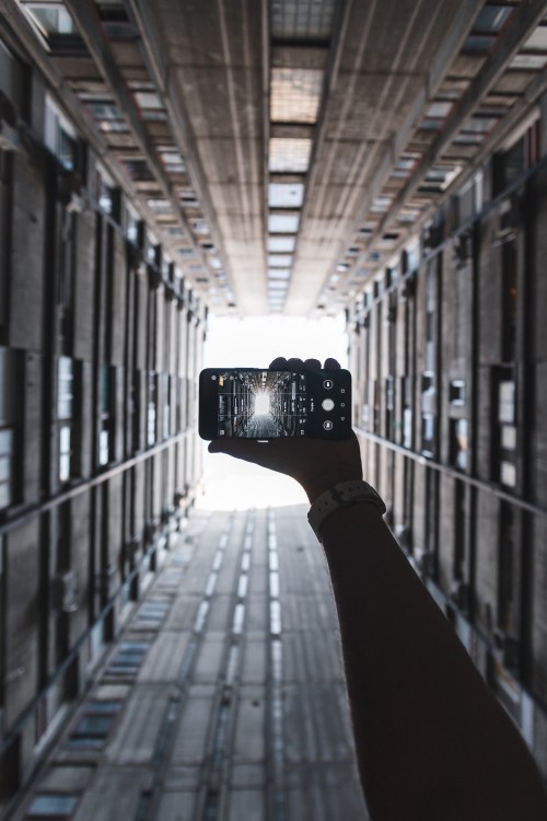 Image person holding black camera in between of building during daytime