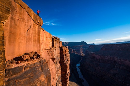 Image person standing on brown rock formation during daytime