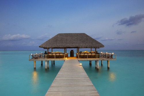 Image brown wooden beach house on blue sea under blue sky during daytime