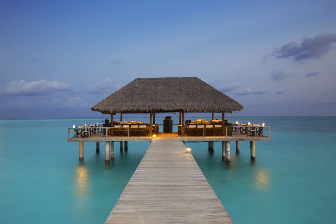 Maison de Plage en Bois Marron Sur Mer Bleue Sous Ciel Bleu Pendant la Journée. Wallpaper in 5760x3840 Resolution