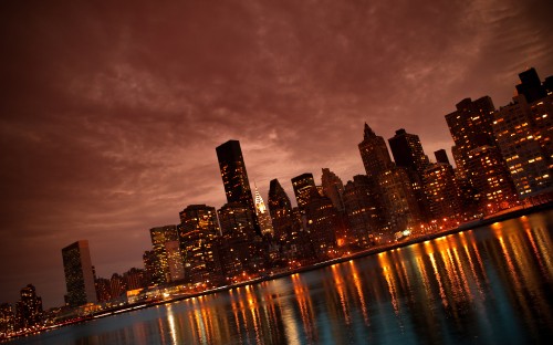 Image city skyline across body of water during night time