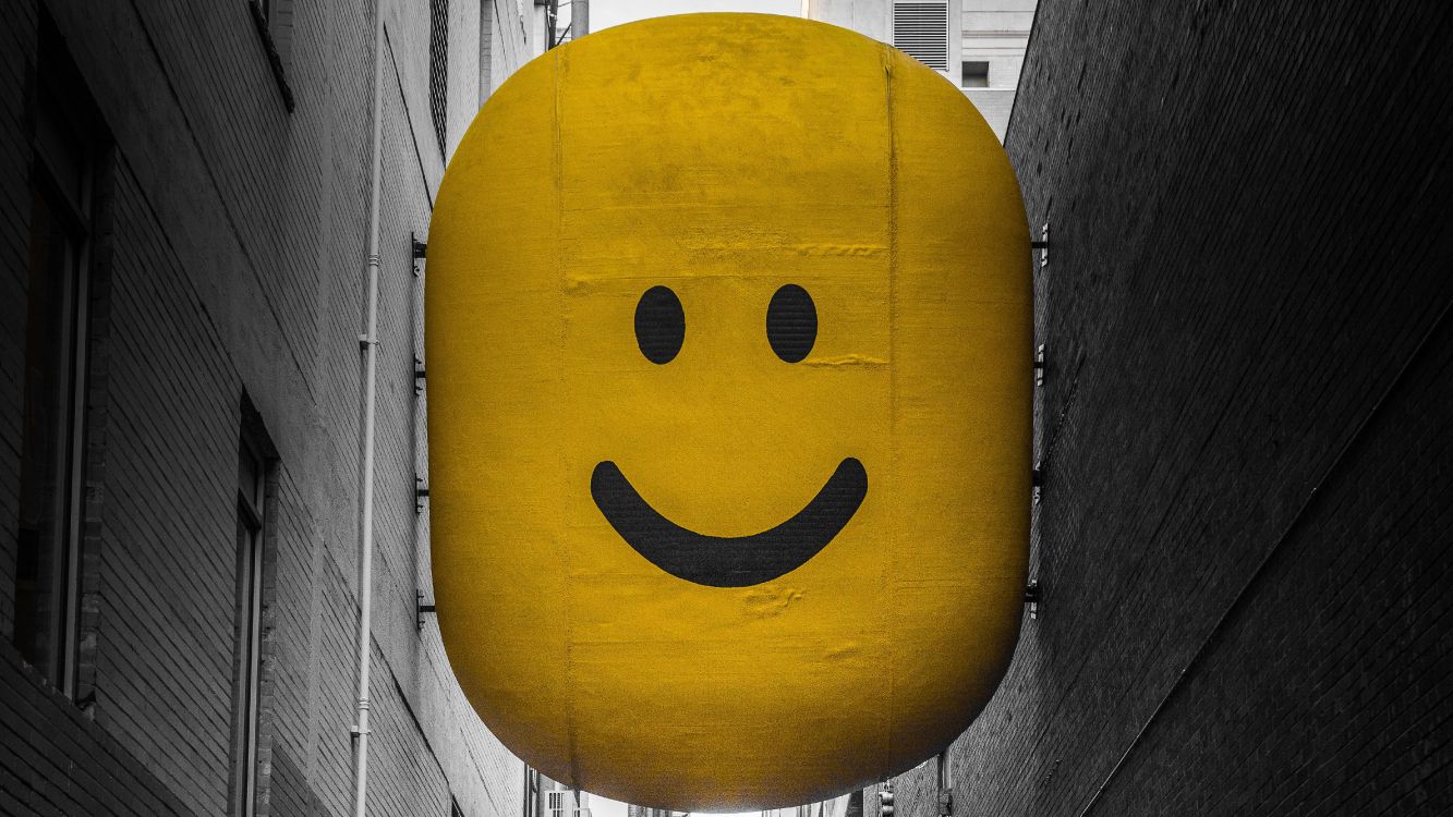 yellow smiley balloon on gray wooden plank