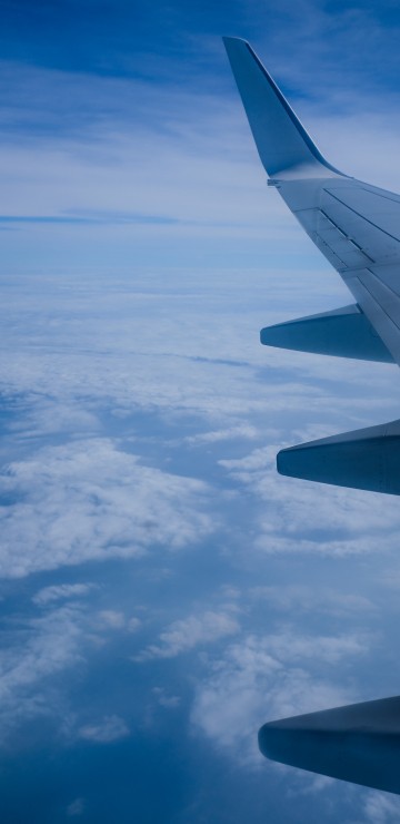 Image white and gray airplane wing under white clouds and blue sky during daytime