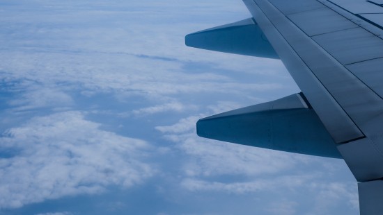 Image white and gray airplane wing under white clouds and blue sky during daytime