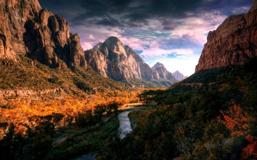 Image river between green grass and trees near mountains under white clouds and blue sky during daytime