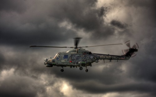 Image green and black helicopter under gray clouds