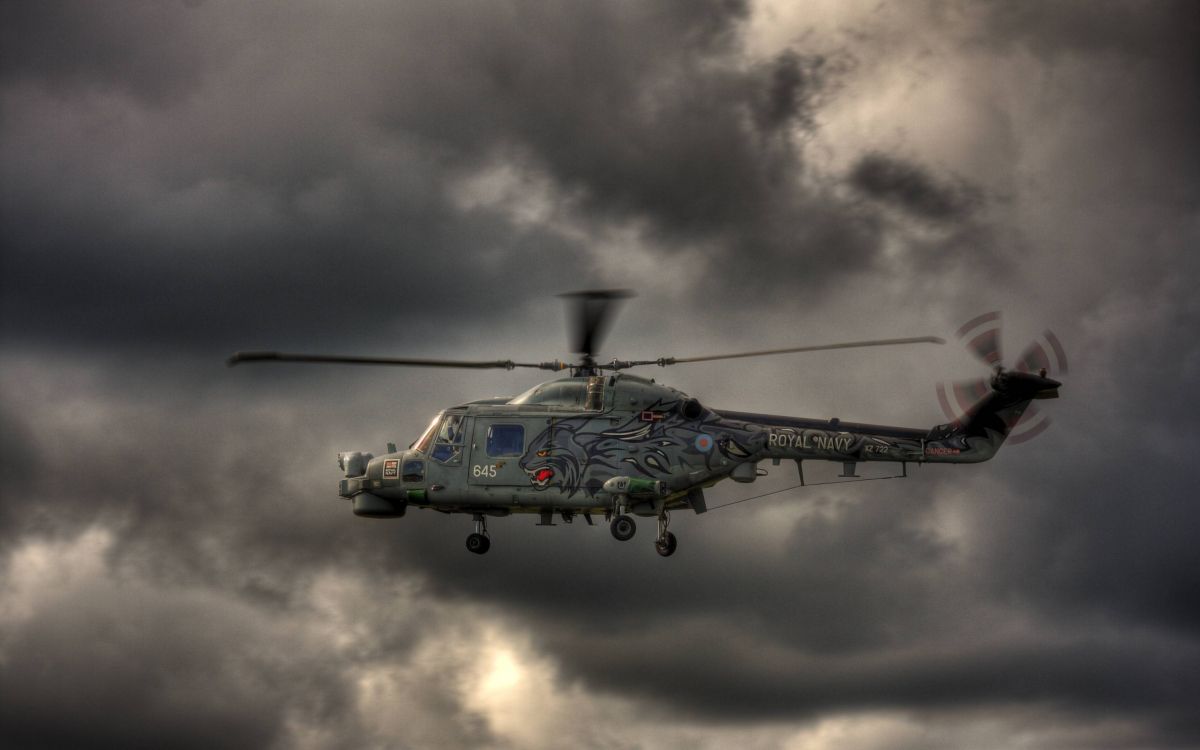 green and black helicopter under gray clouds