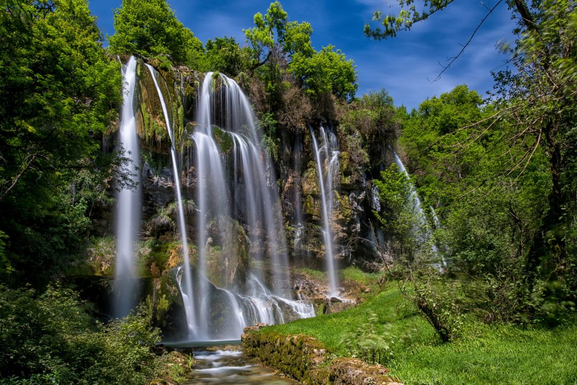 Cascades Sur Terrain D'herbe Verte Sous Ciel Bleu Pendant la Journée. Wallpaper in 3000x2000 Resolution