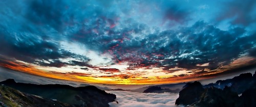 Image silhouette of person standing on rock formation under blue and white cloudy sky during daytime