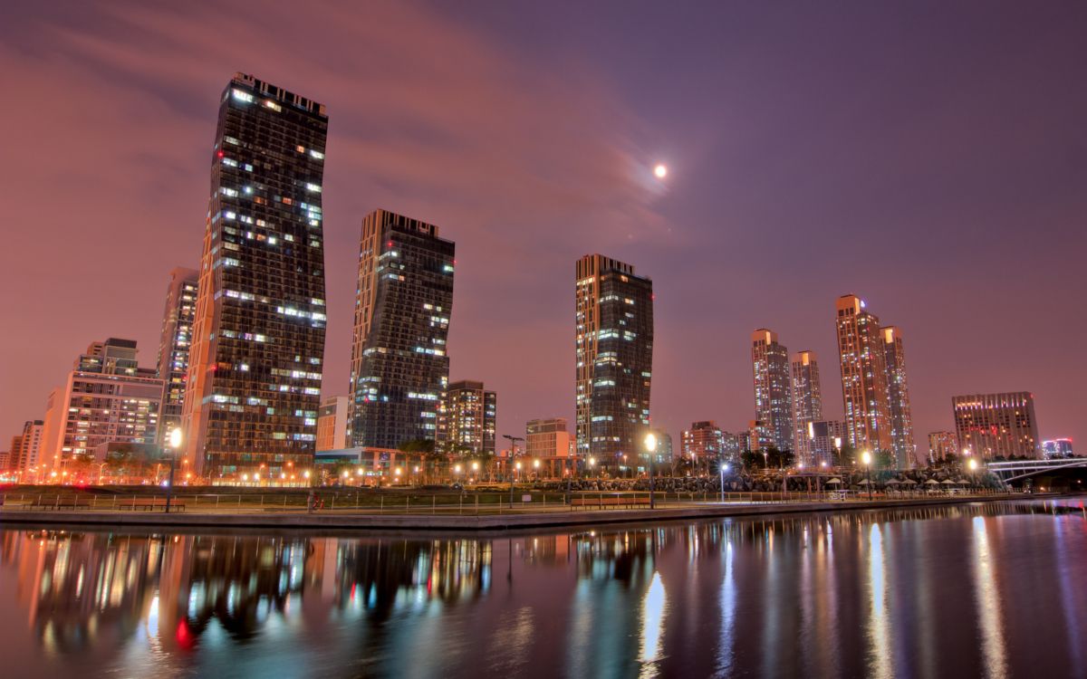 city skyline across body of water during night time