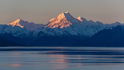 Image snow covered mountain near body of water during daytime