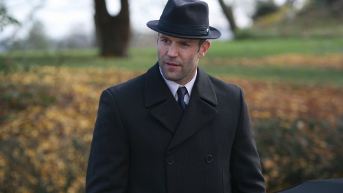 Image man in black suit jacket and black fedora hat standing on green grass field during daytime