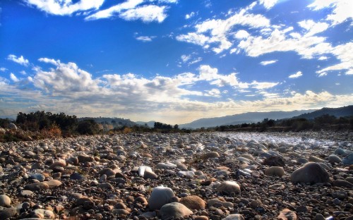 Image gray and black stones on seashore under blue sky during daytime