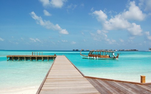 Image brown wooden dock on blue sea under blue sky and white clouds during daytime