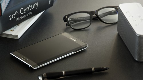 Image black framed eyeglasses beside black samsung android smartphone