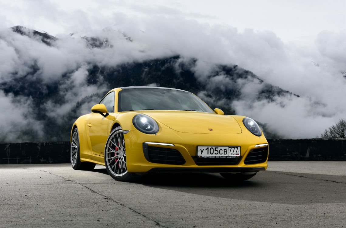 Gelber Porsche 911 Auf Schwarzer Asphaltstraße Unter Grauen Wolken. Wallpaper in 4096x2697 Resolution