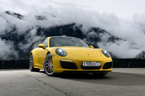 Image yellow porsche 911 on black asphalt road under gray clouds