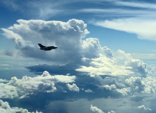 Image black airplane flying under white clouds during daytime